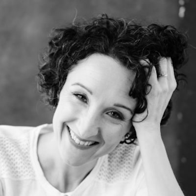 A woman with curly dark hair resting her head on her hand.