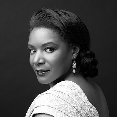 A black women with hair tied up and wearing sparkly earrings