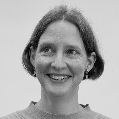 A black and white headshot of a woman with medium-length hair and earrings smiling.
