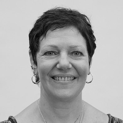 A black and white headshot of a woman with short dark hair and hoop earrings smiling.