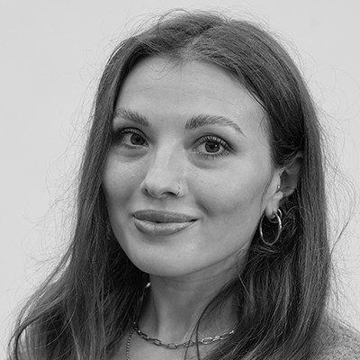 A black and white close-up of a woman with long dark hair wearing a necklace and earring.