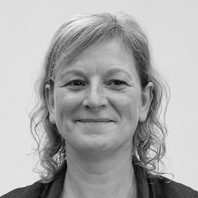 A black and white headshot of a woman with long blonde hair smiling.