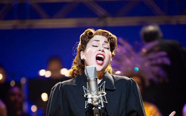 A woman singing into a microphone on stage