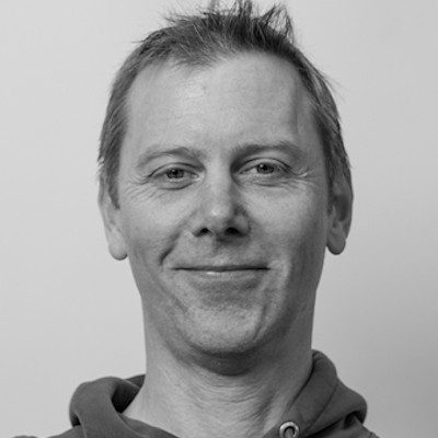 A black and white portrait of a man with short hair wearing a hoodie.