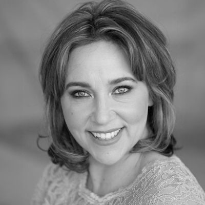 A black and white portrait of a woman with medium length dark hair, smiling.