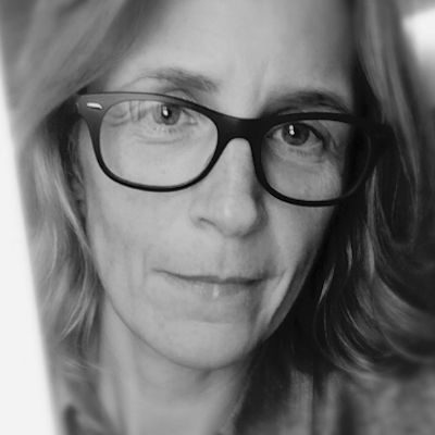 A black and white image of a woman wearing glasses with long, light hair.