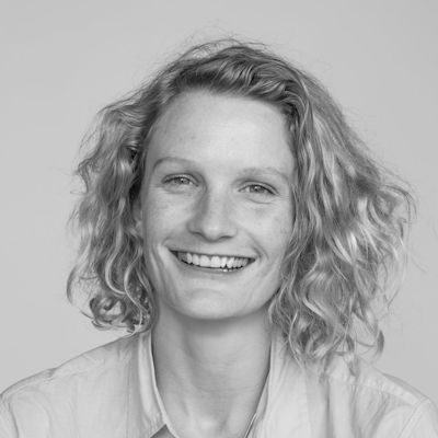 A black and white portrait of a woman with long light hair smiling.
