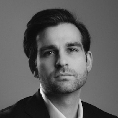 A black and white portrait of a man with short dark hair wearing a suit.