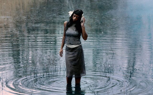 A woman standing on a pool of still water.