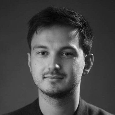 A black and white close-up of a man with short dark hair and a small goatee beard.