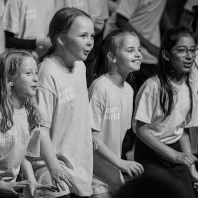 A black and white photograph of the Opera North Young Voices choir -a group of children singing in unison.