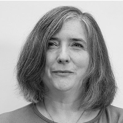 A black and white headshot of a woman with long, medium coloured hair.