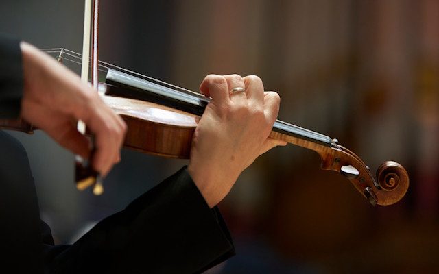 A close-up of a violin being played with a bow.