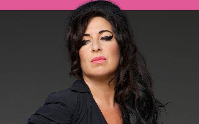 A woman with Amy Winehouse's distinctive hair parting and style, wearing a dark shirt.