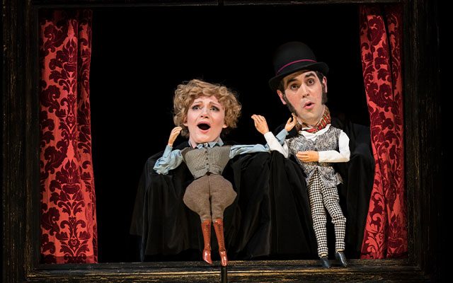 Two people with puppets as bodies performing a Punch and Judy type show.