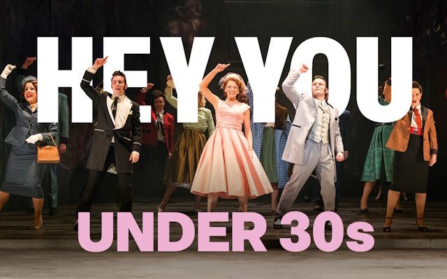 A group of people dancing on stage in 50s styled clothing.