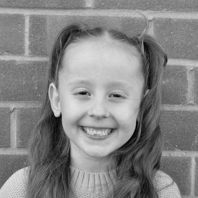 A black and white close-up of a girl with long dark hair and light jumper.