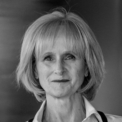 A black and white close-up of a woman with long light-coloured hair wearing a white shirt.