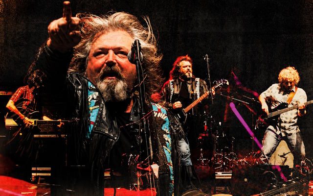 Clearwater Creedence Revival in performance - a band on stage playing electric guitars, bass and drums.