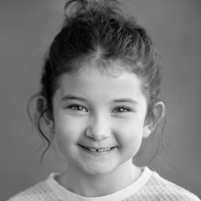 A black and white close-up of a girl with her hair tied up, wearing a light jumper.
