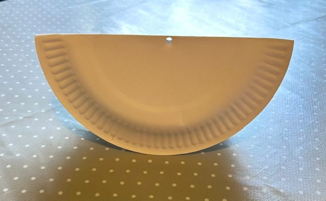 A paper plate with a hole cut at the top middle edge.
