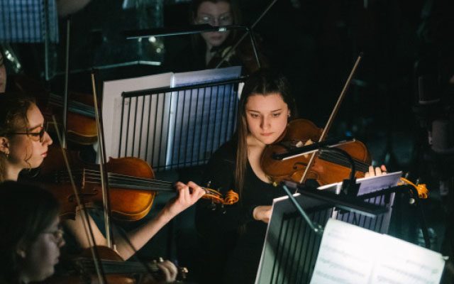 Violin players, playing as part of an orchestra.