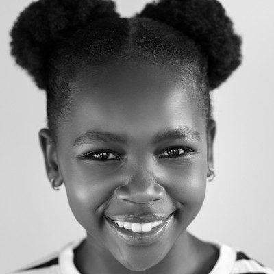 A black and white close-up of a girl with her curly hair styled in two high puffs.