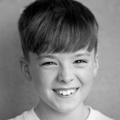 A black and white headshot of a boy with medium-length dark hair.
