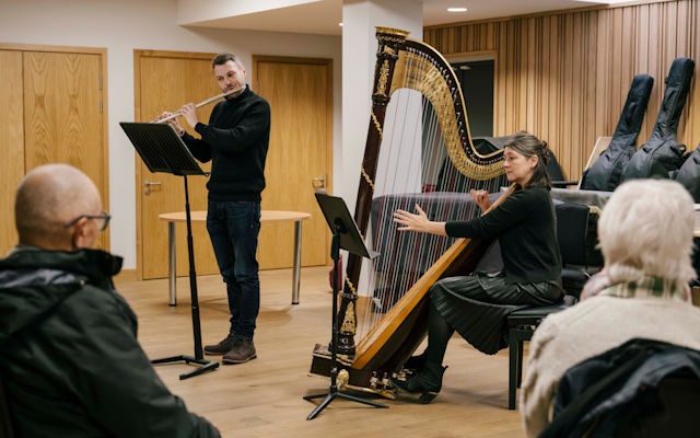 A man playing a flute next to a woman playing the harp during an Opera North event.