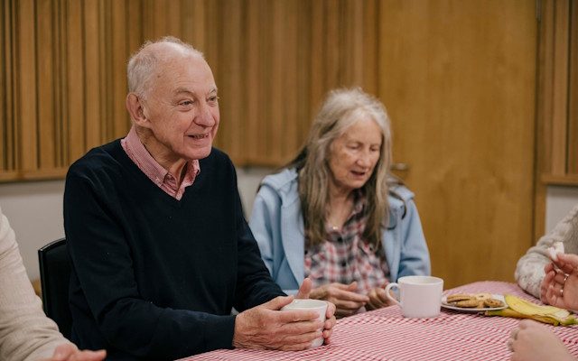 An older man and woman drinking tea at a table during an Opera North event.