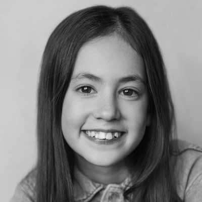 A black and white close-up of a girl with long dark hair, wearing a light-coloured top.