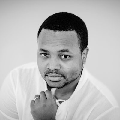 A black and white close up photograph of a man with a white shirt.