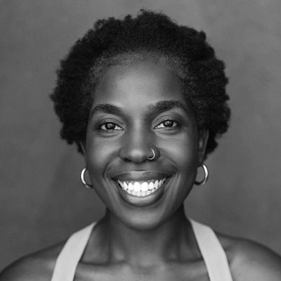 A black and white close-up of a woman smiling with hoop earrings and short dark hair.
