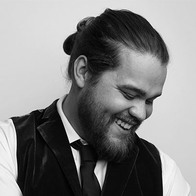 A white man with a beard and long hair tied up in a bun