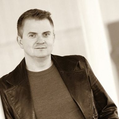 White man with short hair wearing a leather jacket.